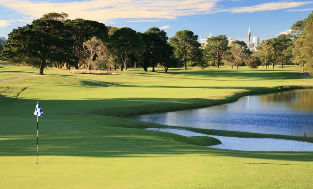 Australian amateur golfer aaron baddeley lines up his putt while his caddie holds the flag during his second round